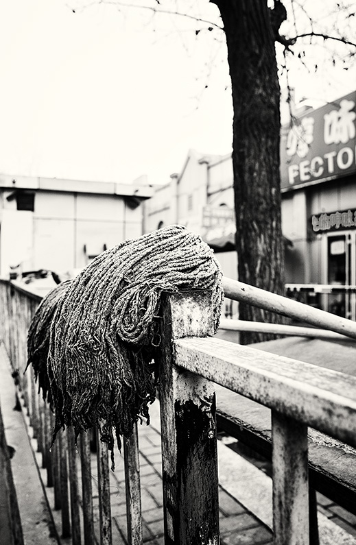 Two mops resting on a metal railings on Yabao Road, Russia Town, Beijing, China.