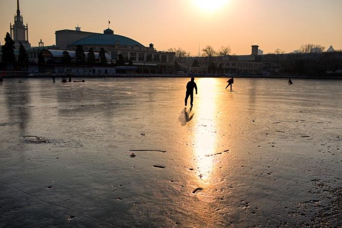 Skater skating on the sun's reflection in the ice of the marina at the Nanchang River, Xicheng, Beijing, China.