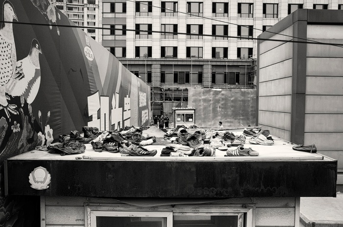 A collection of shoes thrown on the roof of a shed outside a construction site on Linglong Road, Cishousi, Haidian, Beijing, China.